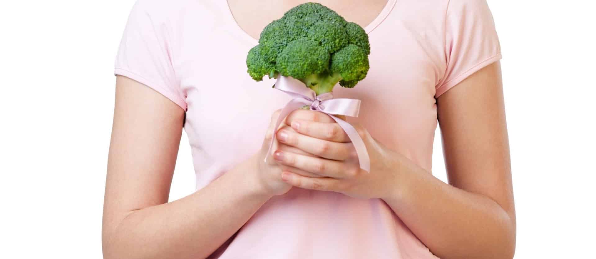 woman holding a piece of broccoli with a pink ribbon tied around it