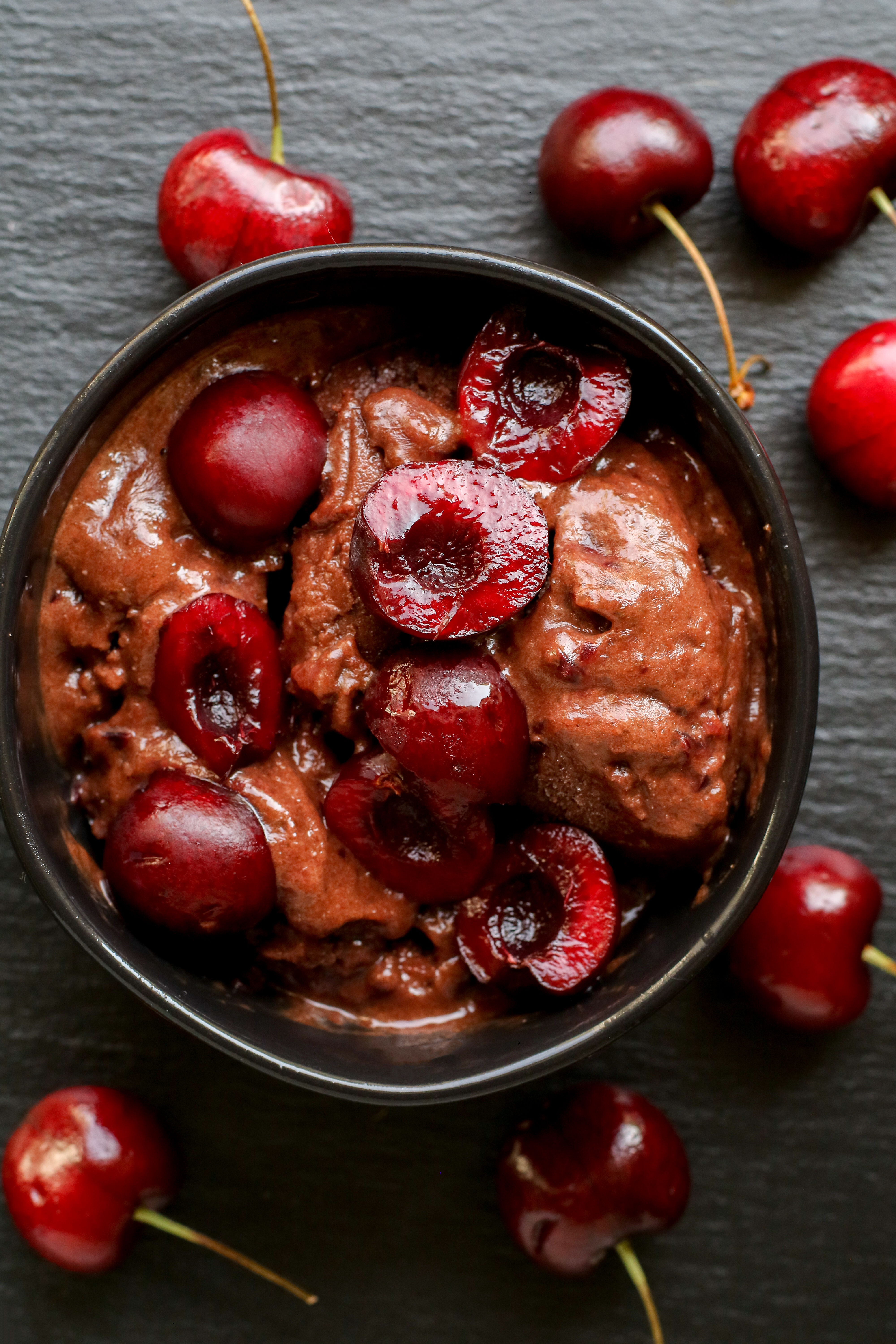 bowl of chocolate cherry nice cream topped with halved cherries